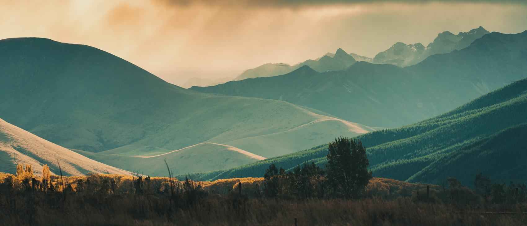 Vallée de collines et de montagnes au lever du jour, lumière chaude sur les crêtes