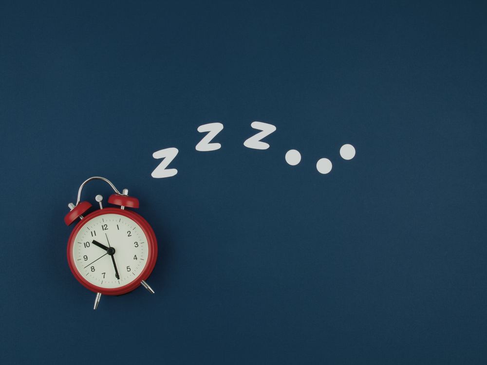 Petit réveil rouge posé à plat, avec des « z » évoquant le sommeil